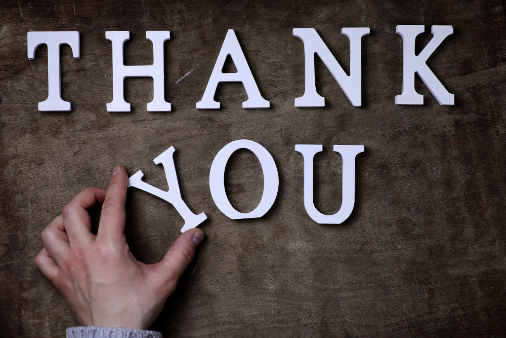 Hand placing block letters to spell out "thank you"