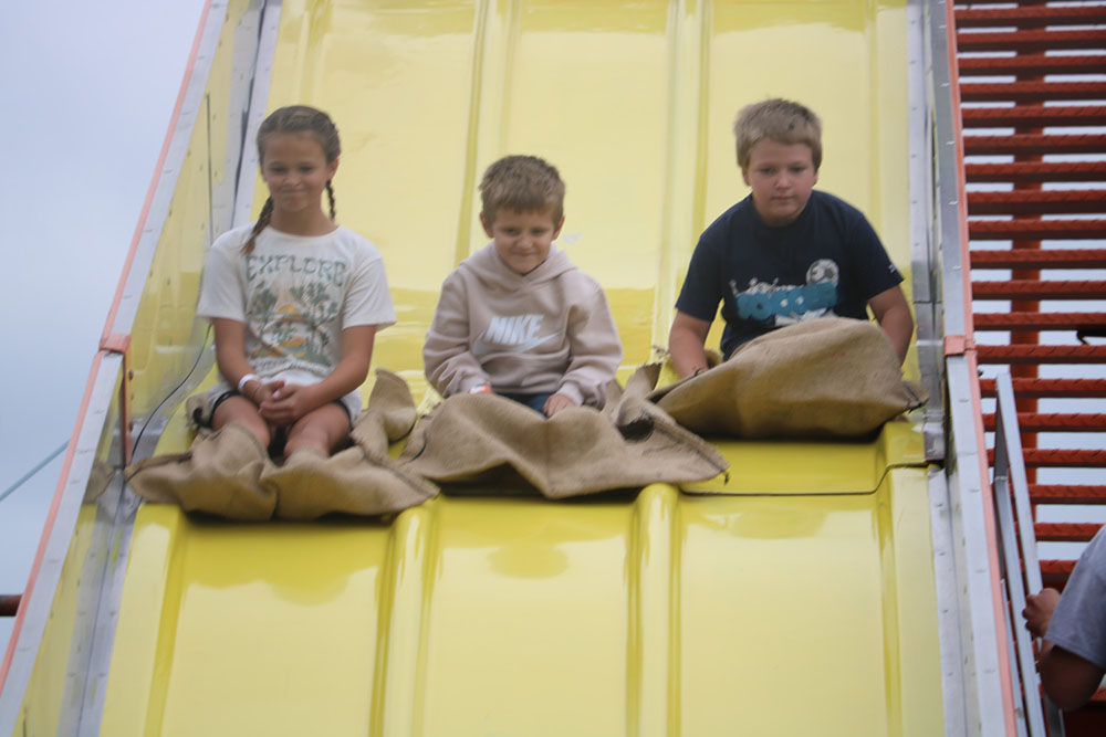 Three children riding down the slide at the 2023 Hardin County Fair.
